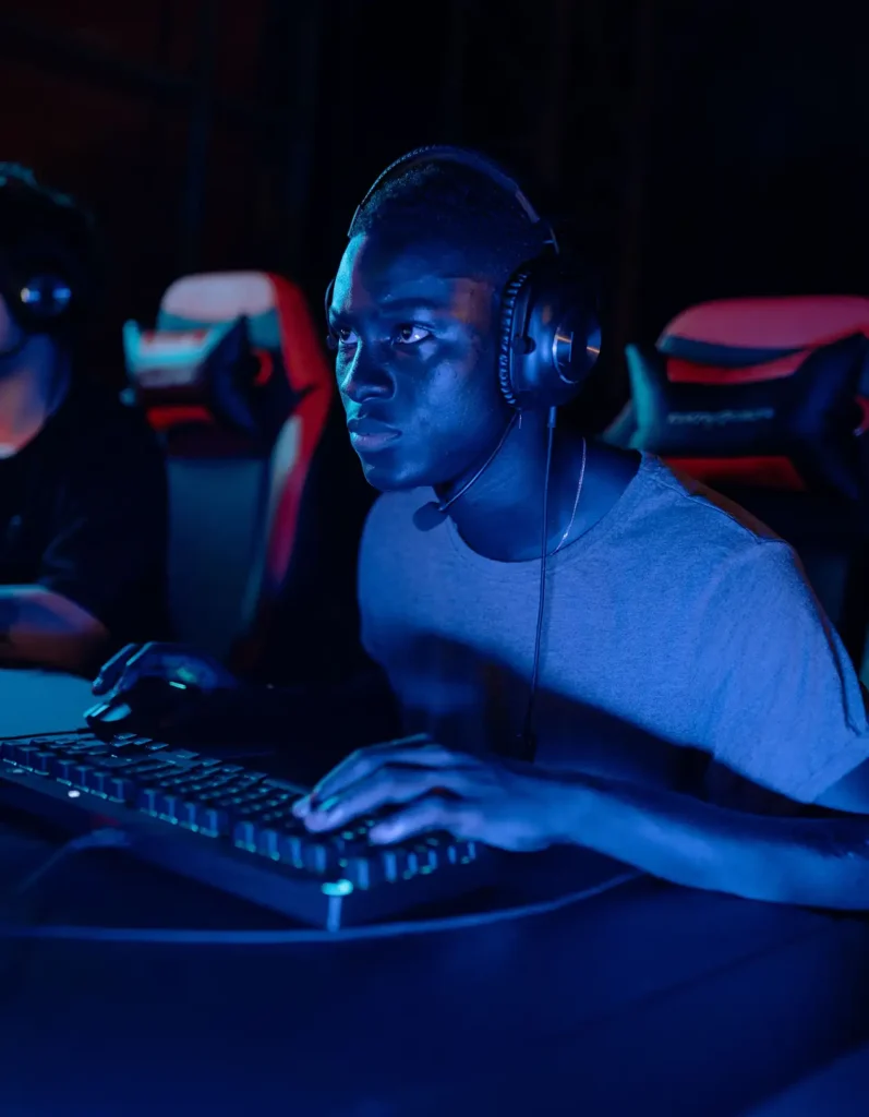 Jogador de eSports concentrado, a utilizar um teclado mecânico e auscultadores para jogos durante uma partida multijogador online num centro de jogos profissional.