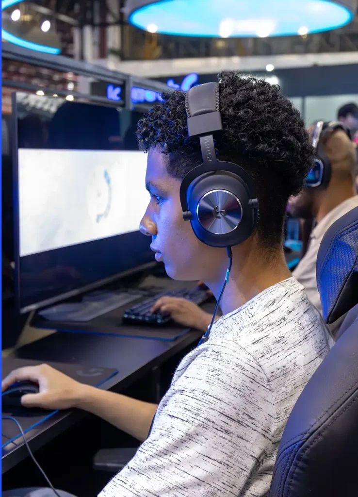 Jovem jogador de e-sports com auscultadores de jogos, a competir num computador de alto desempenho, num clube de jogos moderno com equipamento profissional e iluminação LED.